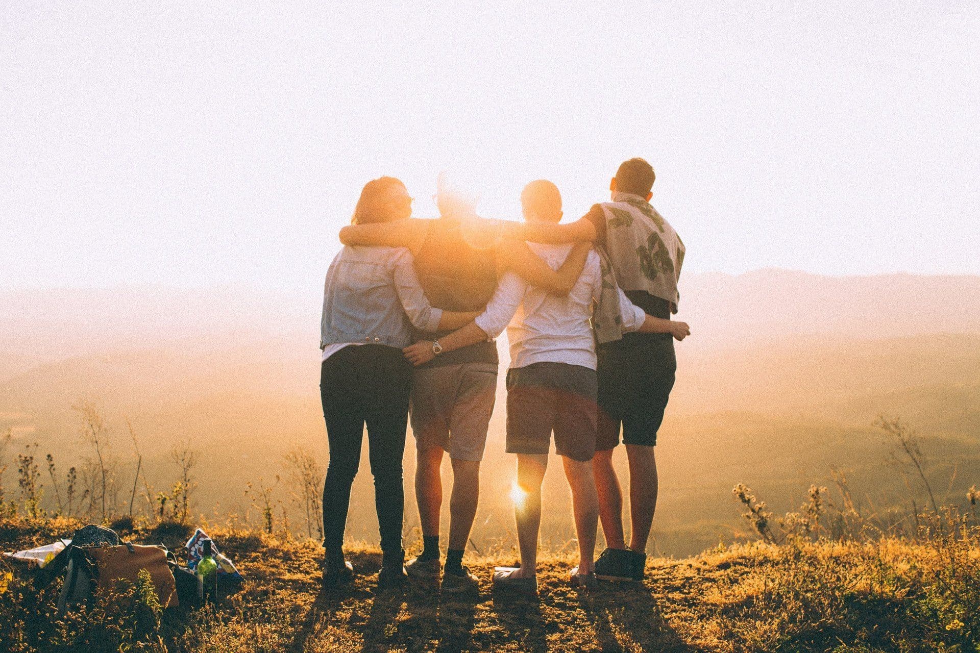 Grupo de amigos abrazados mirando el atardecer